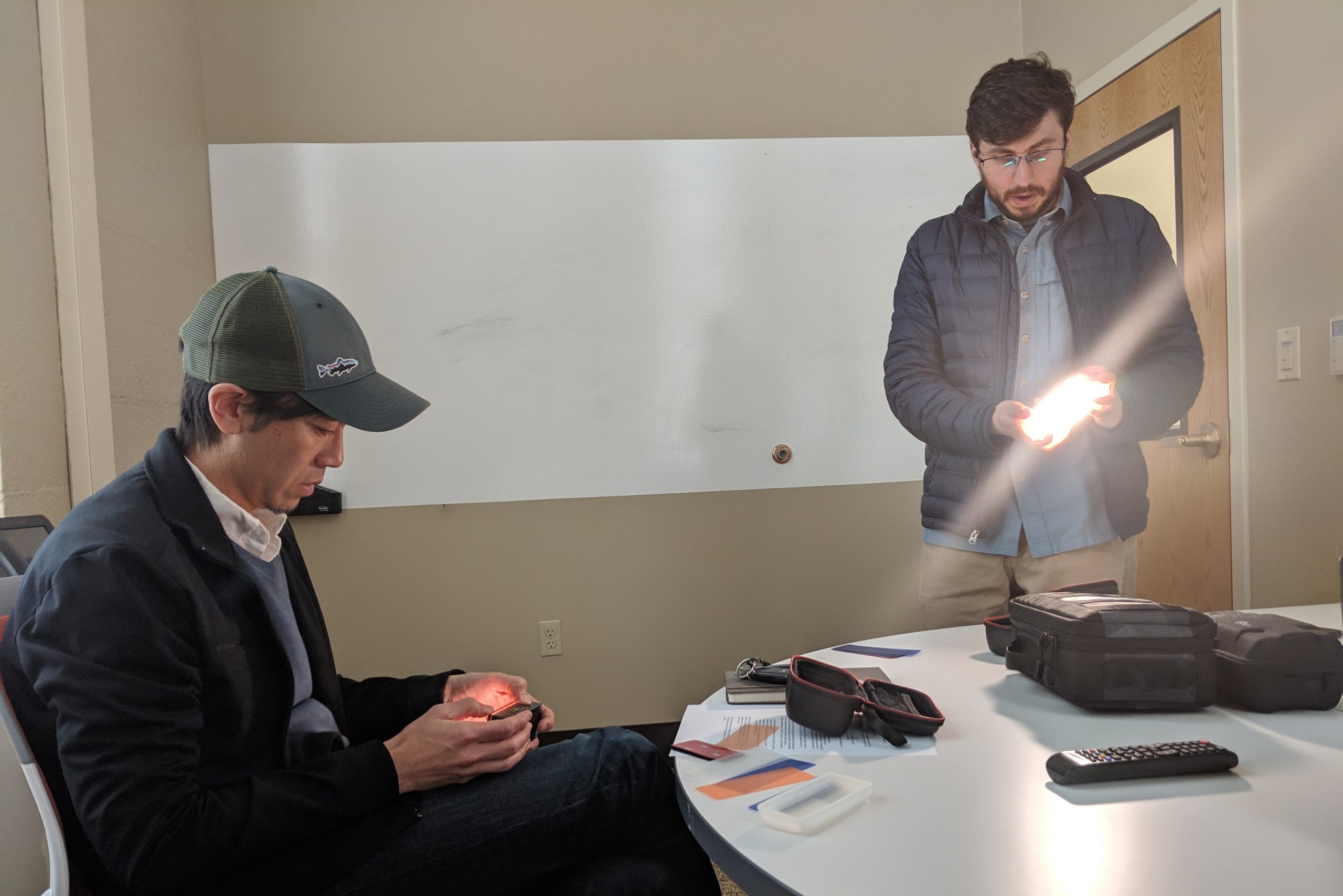 Mizuki Takahashi sitting at a table, Wes standing at the table showing a waterproof LED light