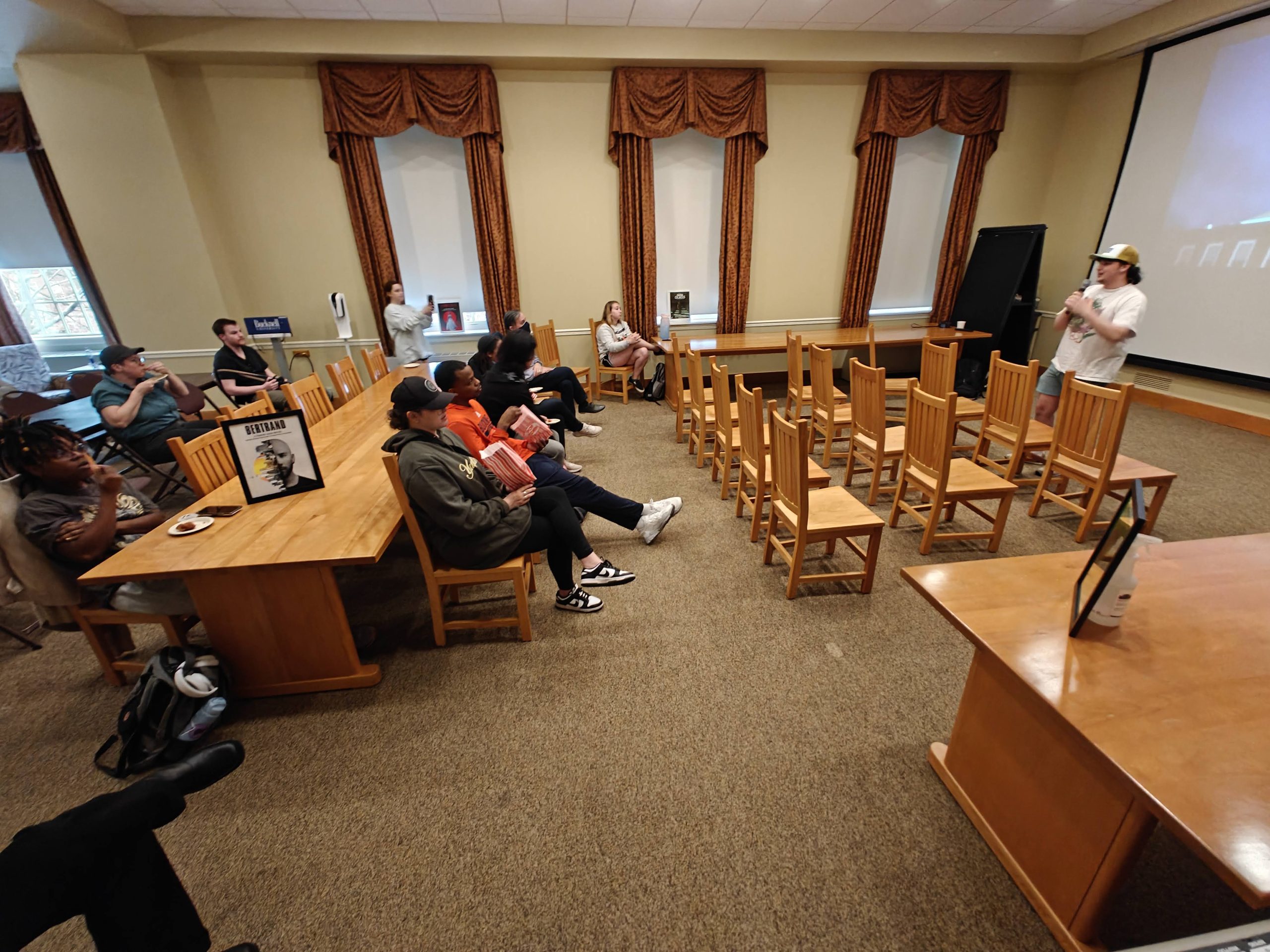 Students and Staff sit in the East Reading Room of Bertrand library and watch an introductory speech by BU Film Club president Jamie Granato