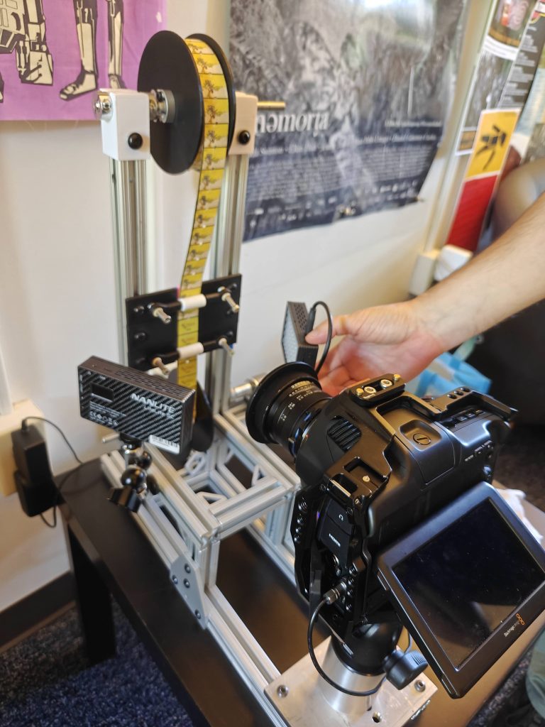 a custum build rig featuring a reel and threaded 1930s Japanese Paper films cascading in front of a cinema camera capturing the frames as they pass